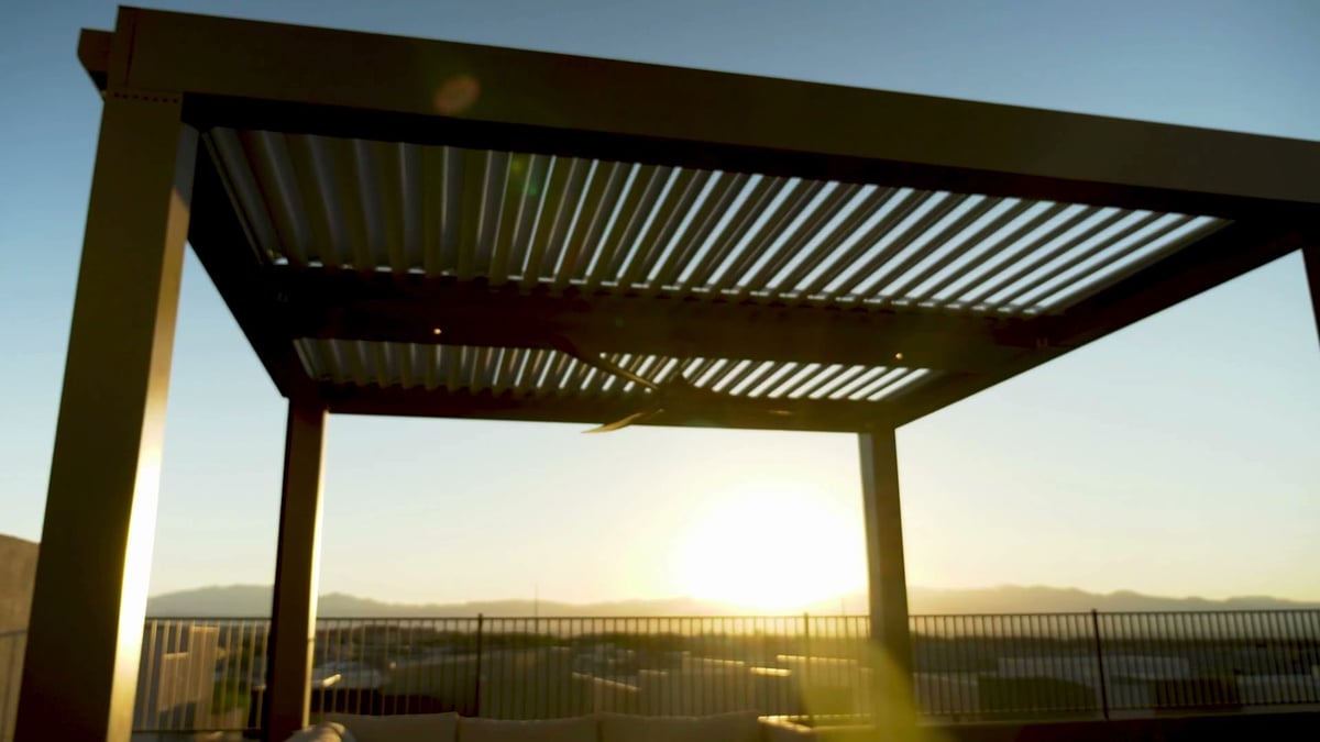 Louvered aluminum pergola over a rooftop patio at sunset